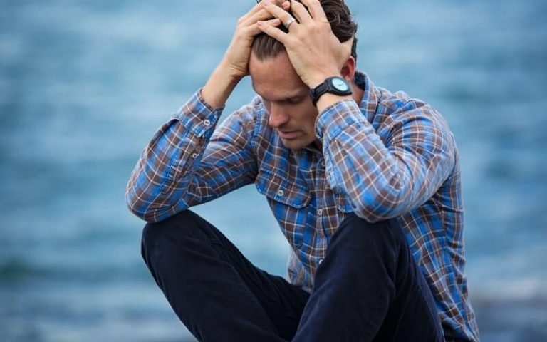 man with anxiety holding his head