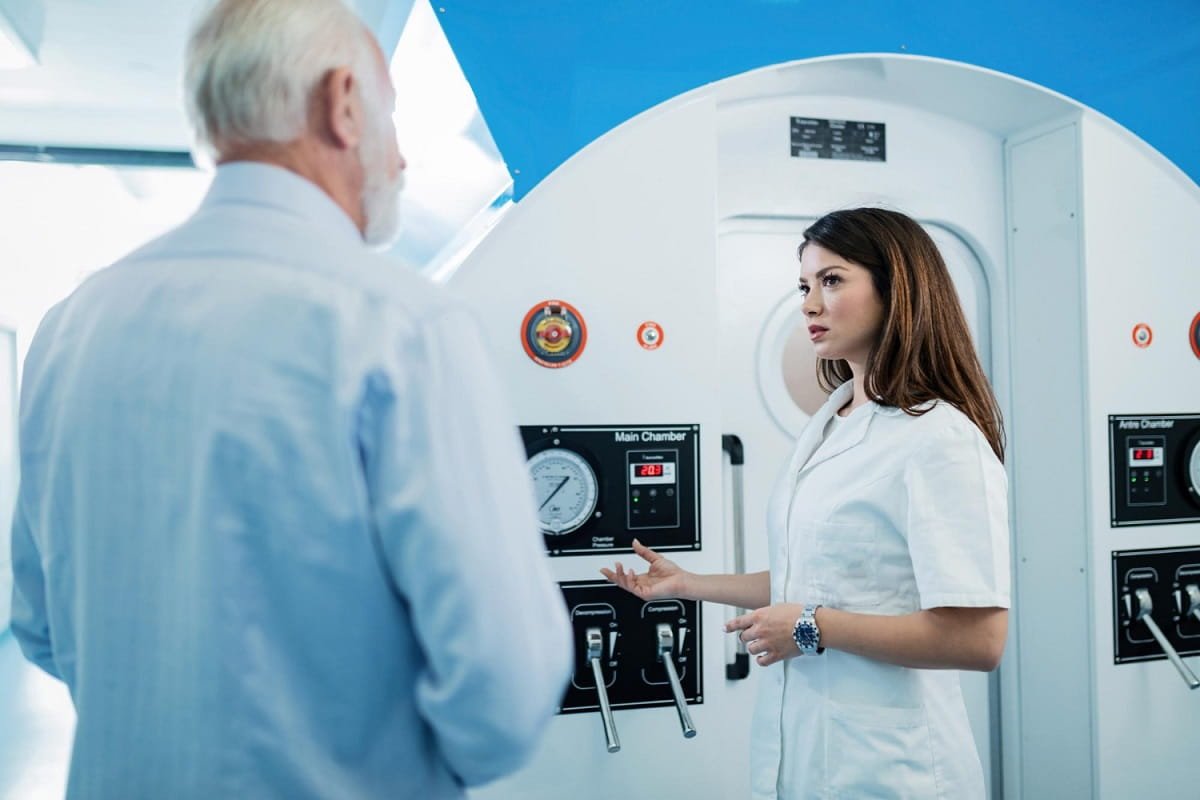 a young doctor standing next to a hyperbaric chamber