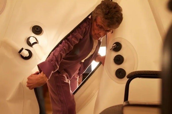 Elderly woman enters the vertical chamber