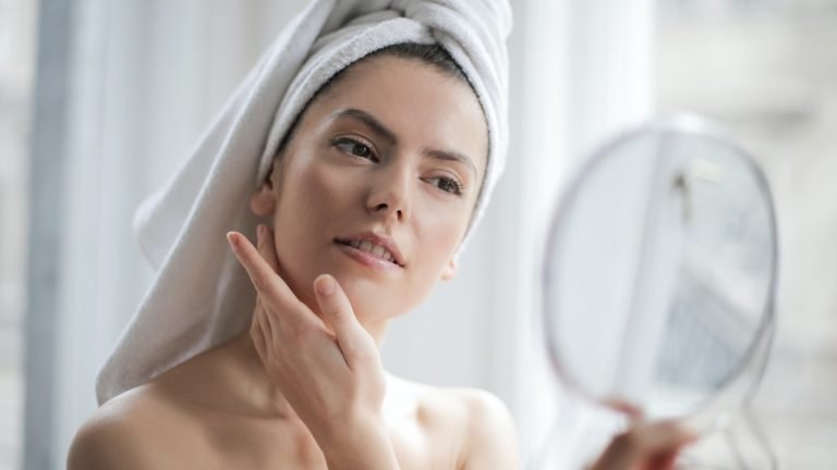 Selective Focus Portrait Photo of Woman With a Towel on Head Looking in the Mirro