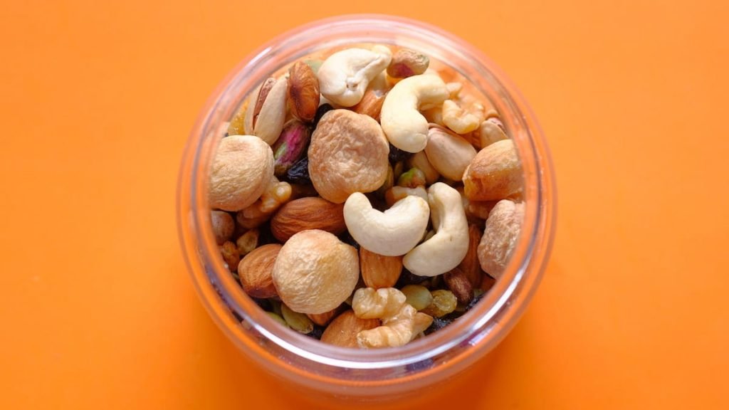 A bowl with mixed nuts on an orange background