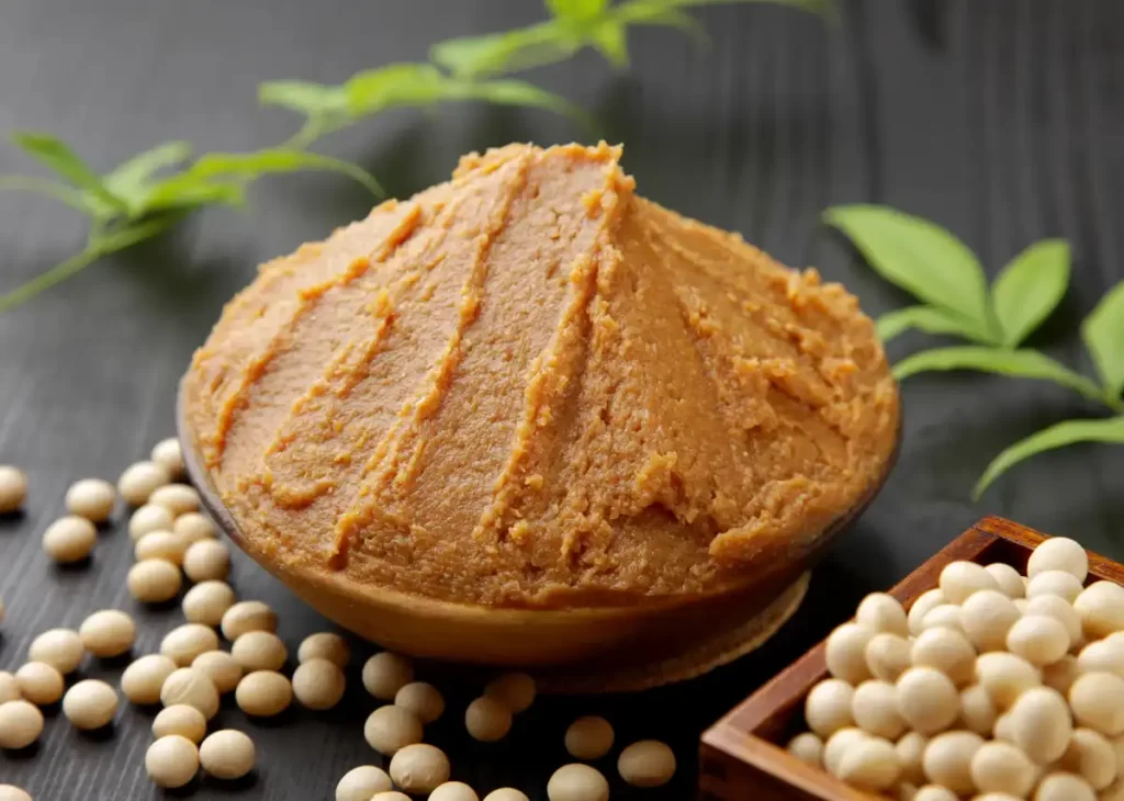 Bowl of miso paste (fermented soybean paste) surrounded by soybeans.
