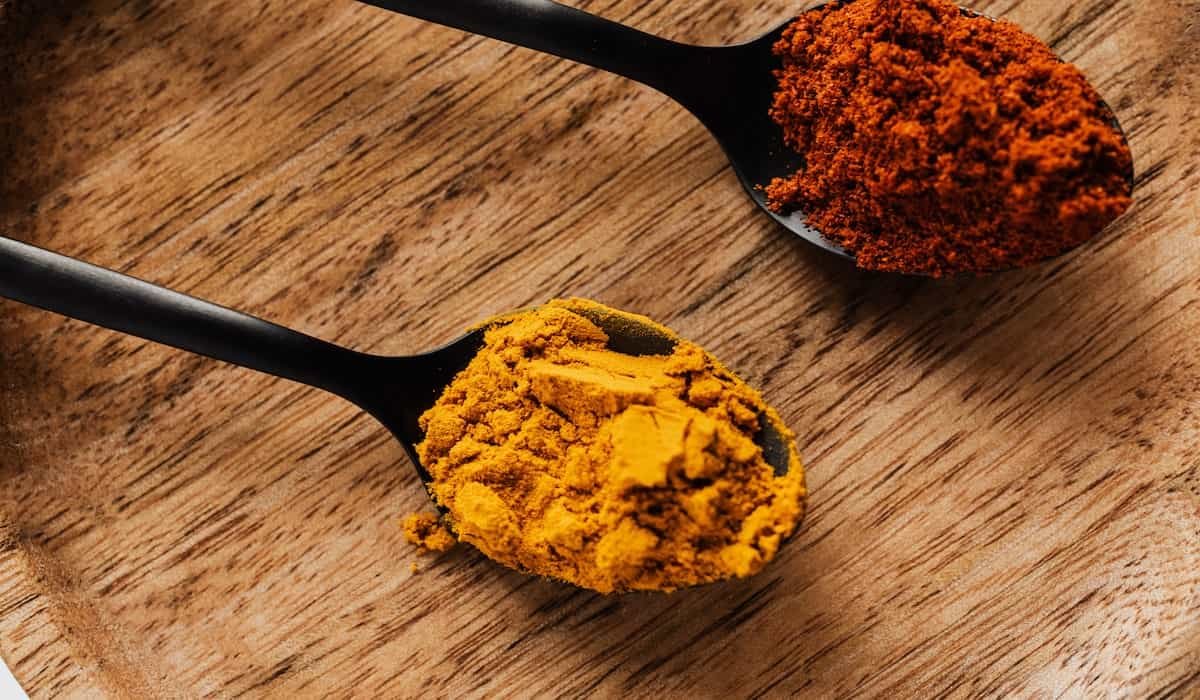 Two table spoons with turmeric and black pepper representing the featured image of the article "what Is The Most Bioavailable Form Of Curcumin?"