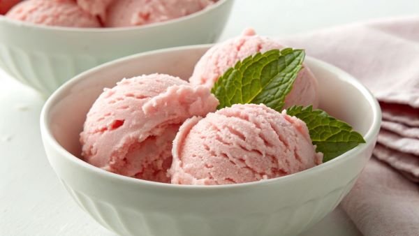 Three balls of Strawberry ice cream in a bowl with a spring of mint 