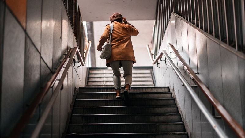 A person seen from the back taking the stairs instead of the elevator.