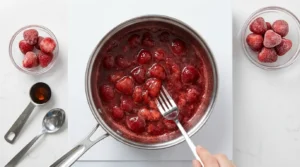 Strawberry compote simmering in a small saucepan showing the correct jam-like consistency for an Erewhon Strawberry Glaze smoothie