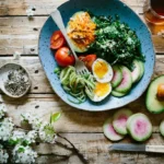 Poached egg with vegetables and tomatoes on blue plate.